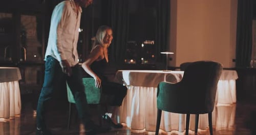 Man pulls chair out for woman then sits