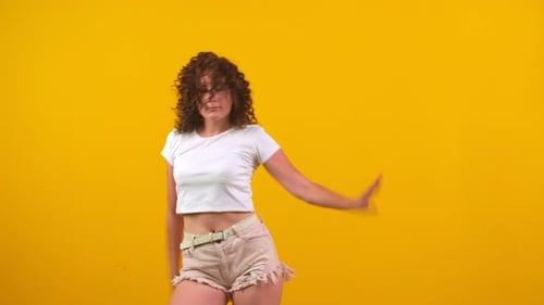 Young Woman Dancing Vigorously on Yellow Background
