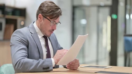 Businessman Celebrating Success on Documents in Office