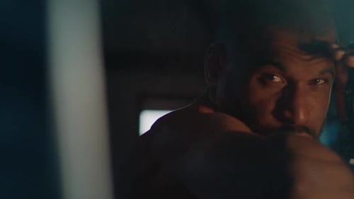 Male Fighter Works Out in the Dark Gym