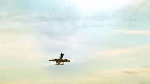 Airplane Flying Overhead Against Sky Background