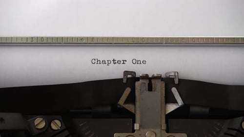 Typing phrase Chapter One on retro typewriter. Close up.