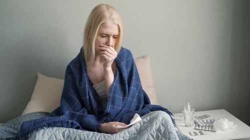 Young Woman Coughing in Bedroom