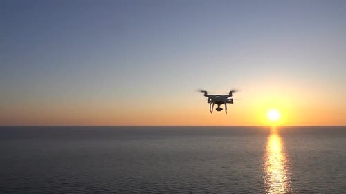 Drohne fliegt über das Meer dem Sonnenuntergang entgegen