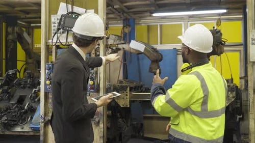 Engineers Inspecting Automated Robotic Arm in Factory