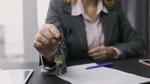 Estate Agent Midsection Offering Keys To Camera