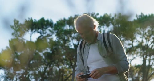 Senior Man Uses Smartphone in Nature