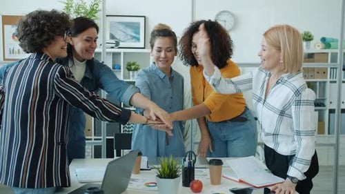 Diverse Women Celebrate Teamwork Success in Office