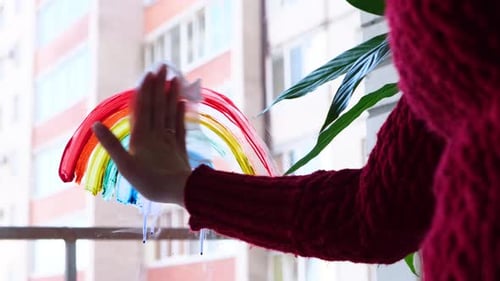 Woman Cleaning a Window with Rainbow Drawing