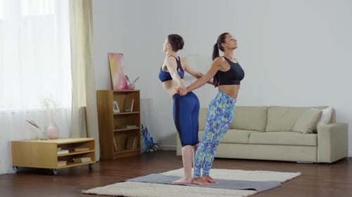 Two Women Practicing Yoga in a Living Room