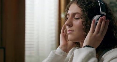 Young Woman Puts on Headphones and Listens