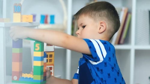 Child Plays with Colorful Building Blocks on Shelf
