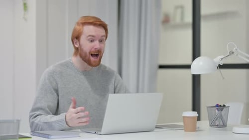 Red-haired Man Video Calling on Laptop in Office