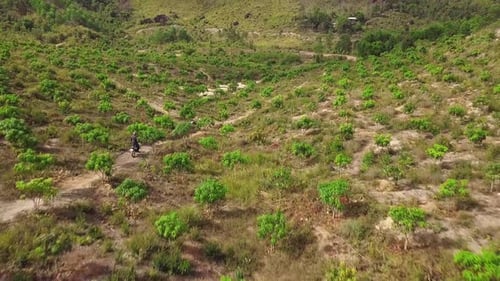 A Motocross Rider Riding Motorbike on the Dirt Road Pathway in the Mountain.