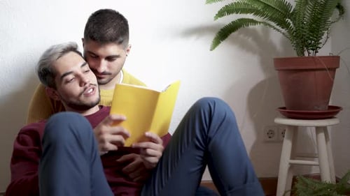 Gay Couple Reading Book Together at Home
