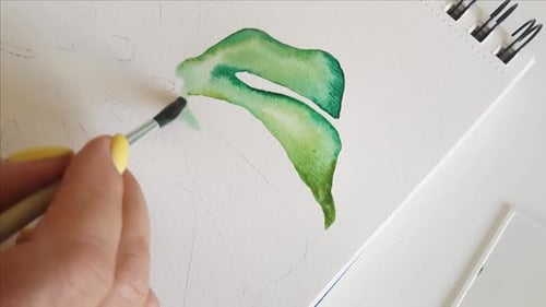 Woman painting Monstera leaf with Watercolors close up