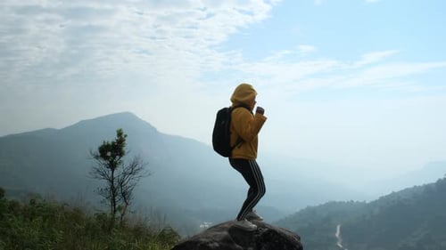 Successful female hikers open arms on top of the mountain.
