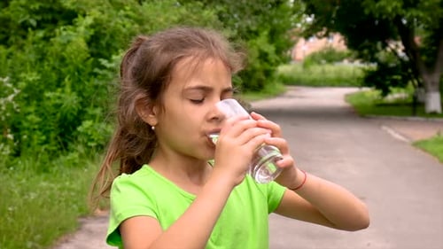 Girl Drinks Water Outdoors on Sunny Day