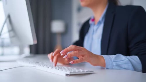 Woman Typing at Computer in Bright Office