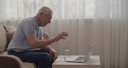 Senior Man Video Calling Using Laptop at Home