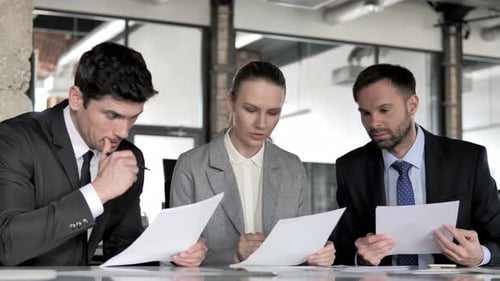 Business Team Analyzes Documents in Modern Office