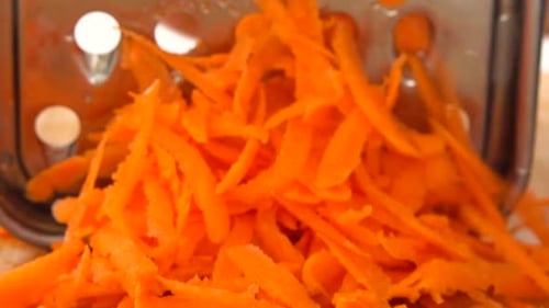 Vibrant Carrot Being Grated into Pieces