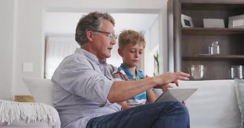 Grandfather and Grandson Using Tablet Together on Sofa
