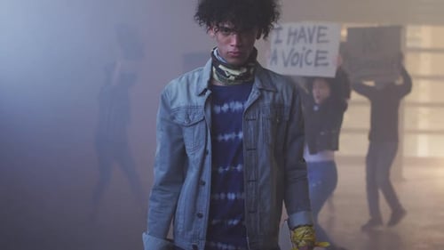 Groupe diversifié de personnes portant des masques et brandissant des pancartes de protestation