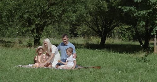 Happy Family Enjoying Picnic in Green Meadow