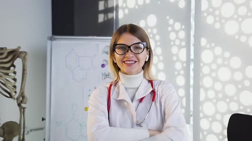 Doctora en medicina con gafas y bata blanca con estetoscopio en el cuello sonriendo