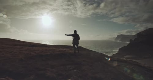 Silhouette Person Arms Outstretched on Scenic Coast