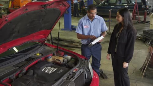 Mechanic in auto repair shop helps customer