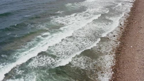 A View of the Ocean and Waves Crashing Against the Rocky Shore with White Foam