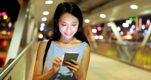 Woman use of smart phone in city at night