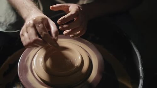 Mains d'artisan formant une assiette en argile sur un tour de potier au Ralenti