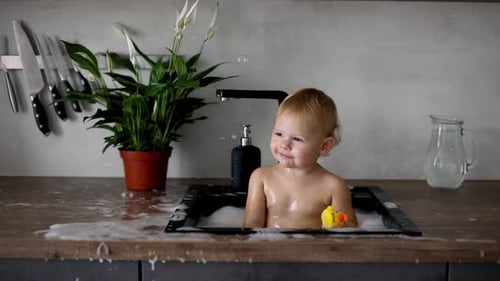 Happy Infant Playing in Kitchen Sink With Bubbles
