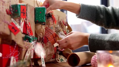 Manos haciendo calendario de adviento navideño en casa