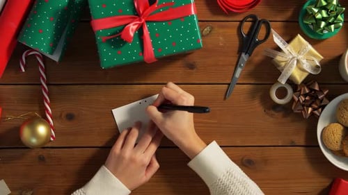 Person Writing Christmas Gift Tag Overhead