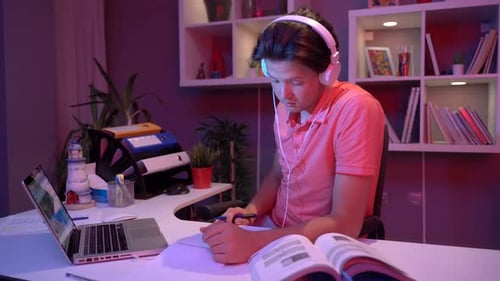 Student Studying with Computer and Book at Night