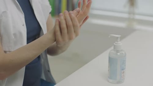 Person Using Hand Sanitizer in a Workplace