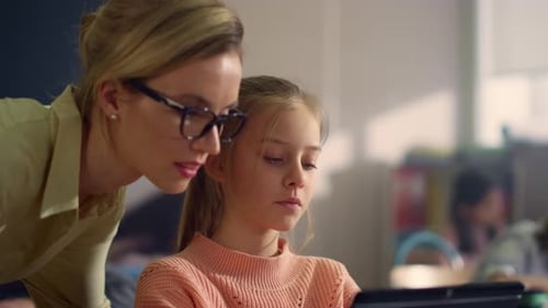 Child Using Tablet in Classroom with Teacher
