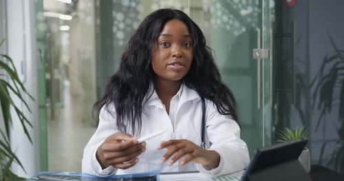 Médico femenino en bata blanca con estetoscopio que organiza videoconferencias y socios de consultoría