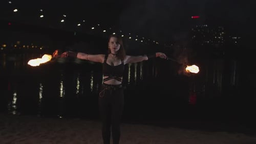 Woman Performing with Fire Staffs at Night