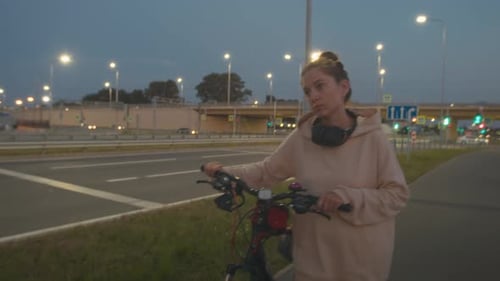Woman rides a bike along the night alley in the city