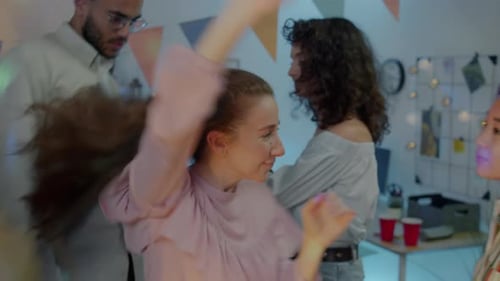 Modern Young Woman Dancing with Cheerful Friends During Exciting Party at Home at Night