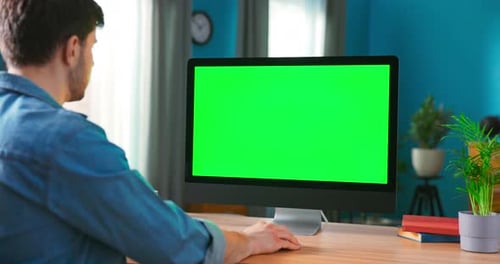 Over the Shoulder Shot of Mans Hands Typing on a Keyboard Computer with Green Mockup