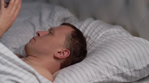 Man Using Mobile Phone Lying in Bed