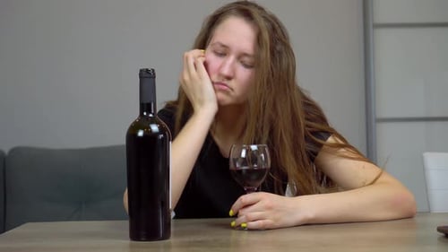 Sad Young Woman with Wine Bottle and Glass