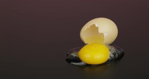 Egg Yolk Poured Out From Broken Eggshell on Black Surface