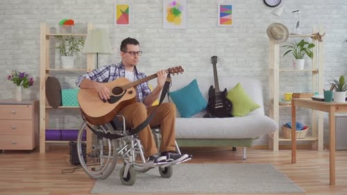 Young Man Plays Guitar in Wheelchair at Home